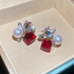 Macro view of silver studs with square red gemstone, white pearl and zircon accents