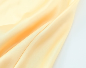 Détail macro du satin de soie champagne montrant des draperies et une texture lisse