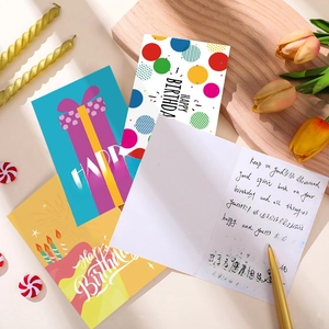 Set of 24 colorful birthday cards with envelopes and stickers on a wooden display