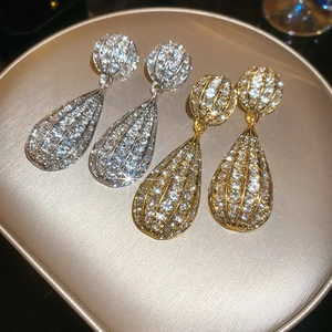 Close-up of elegant teardrop earrings with crystals in gold and silver finish