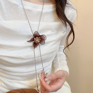 Close-up of brown mesh flower necklace with diamond accents and silver chain on model