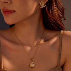 Close-up of elegant gold sun-shaped necklace and earrings set with tiny zircons