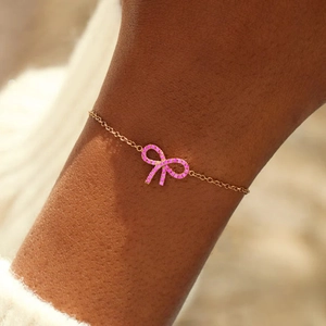 Elegant gold bow pendant bracelet with pink pavé crystals for women on wrist