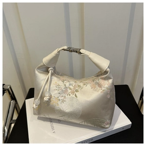 Detail of floral embroidery on a white silk handbag with silver metal buckle and handle
