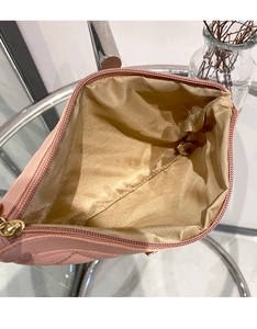 Close-up of pink quilted clutch bag open showing golden fabric lining and metal zipper