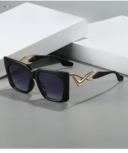 Detail of fashion oversized sunglasses with gold hollowed-out wing design on temples