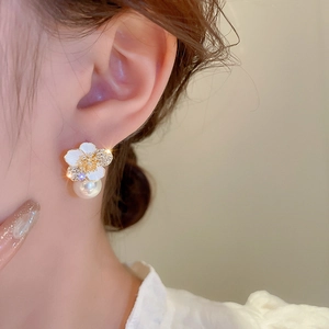 Detail of flower earrings with zircons and pearl pendant worn by model on ear