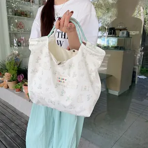 Detail of white canvas tote bag with cute rabbit pattern and green woven handles