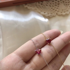 Dettaglio di braccialetti con cuore rosso in oro e argento indossati su un polso femminile