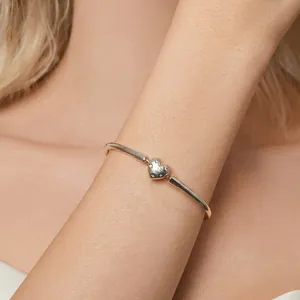 Elegant S925 sterling silver bangle with a hollow heart charm on a model's wrist