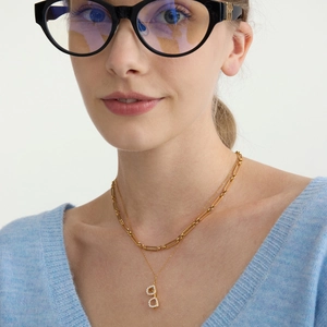 Mehrlagige goldene Halskette mit Brillenanhänger an einem weiblichen Modell