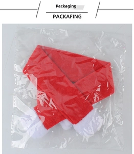 Close-up of red and white Christmas wine bottle scarf with plush pom-poms in packaging