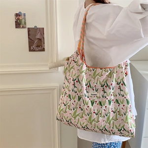 Floral canvas tote bag with tulip patterns shown on shoulder in a minimalist setting