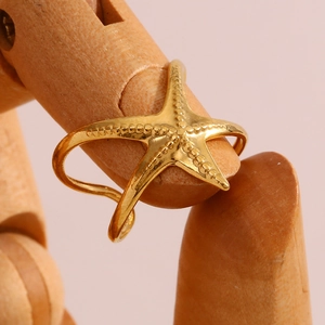 Gros plan d'une bague étoile de mer dorée 18 carats avec des textures biologiques