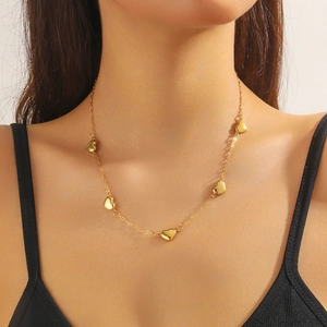 Detailed view of multiple gold heart charms on a sleek chain necklace worn by a model