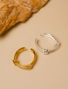 Close-up of gold and silver double-layer knotted rings with a woven texture finish