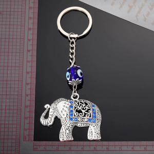 Vintage elephant keychain with evil eye pendant and blue rhinestones on black background