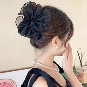 Détail d'une grande pince à cheveux fleurie en mousseline noire sur les cheveux