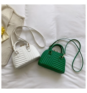 Detail of white and green quilted shell bags with V-shaped stitching and gold hardware