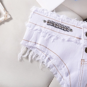 Vista dettagliata di pantaloncini di jeans bianchi con bordi sfrangiati e strass in vita