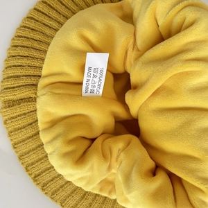 Detail view showing soft yellow fleece lining and 100% acrylic material label on winter hat