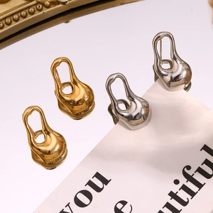 Gros plan de boucles d'oreilles gouttes creuses irrégulières en or et argent polis