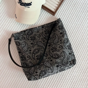 Detail view of grey linen tote bag featuring black Paisley patterns and slim leather strap