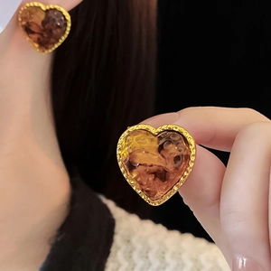 Close-up of a heart-shaped geometric earring with golden frame and amber resin inlay
