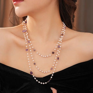 Detail of layered gold necklace featuring purple amethyst beads and small white pearls