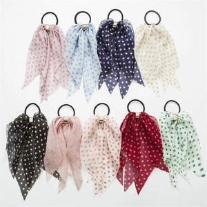 Flat lay of nine colorful polka dot bow hair scrunchies with gold metal buckles