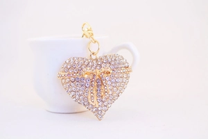 Close-up of golden heart keychain with sparkling rhinestones and a 3D bow detail