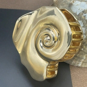 Artistic golden spiral conch hair claw clip with metallic finish for beach vacation style