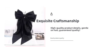 Close-up of large black satin bow hair clip with long streamers and shiny fabric