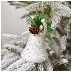 Gros plan de cloche de Noël pailletée blanche avec pommes de pin et nœud en toile