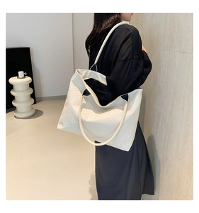 Close-up of a white woven oversized tote bag showing high-quality leather texture