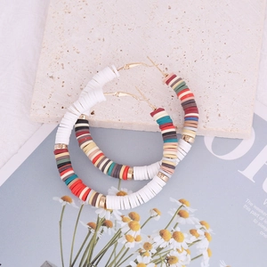 Flat lay of colorful Bohemian polymer clay hoop earrings on a stone slab background