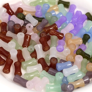 Close-up of colorful bamboo-shaped glass beads for DIY jewelry making in a white dish