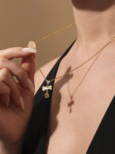 Detail van gouden ketting met zirkoon hart, bot en poot hangers op een model