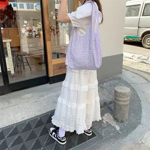Detail of a purple and white gingham canvas tote bag with wide shoulder strap