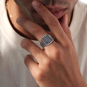 Macro view of men's silver signet ring featuring micro-paved black zircon stones on model