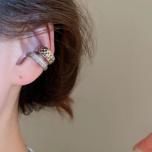 Détail de boucles d'oreilles clips empilables avec finition martelée et zircons sertis