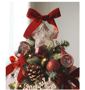 Close-up of mini Christmas tree top with red velvet bow, silver star and pine cones