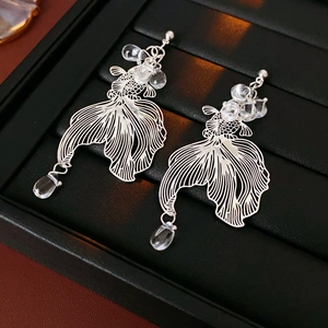 Detail shot of silver koi fish earrings with hollow lines and clear teardrop beads
