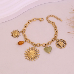 Detail of gold sun and stone charms on a bohemian style multi-element bracelet