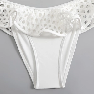 Macro detail of white eyelet fabric and ruffle edges on these women bikini bottoms