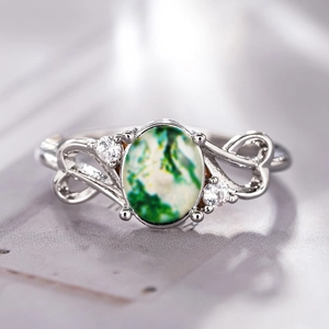 Macro detail of moss agate ring with heart-shaped cutouts and sparkling side stones