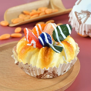 Macro detail of artificial fruit cake with orange slice and blueberry on a wooden tray