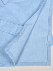 Vue macro de la texture denim bleu clair et détails de couture du col en V sur le haut