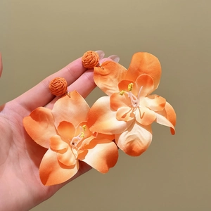 Detalle macro de pendientes colgantes con flores de hierba de rafia naranja vivo