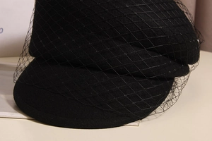 Close-up of black wool newsboy cap featuring elegant polka dot mesh veil detailing